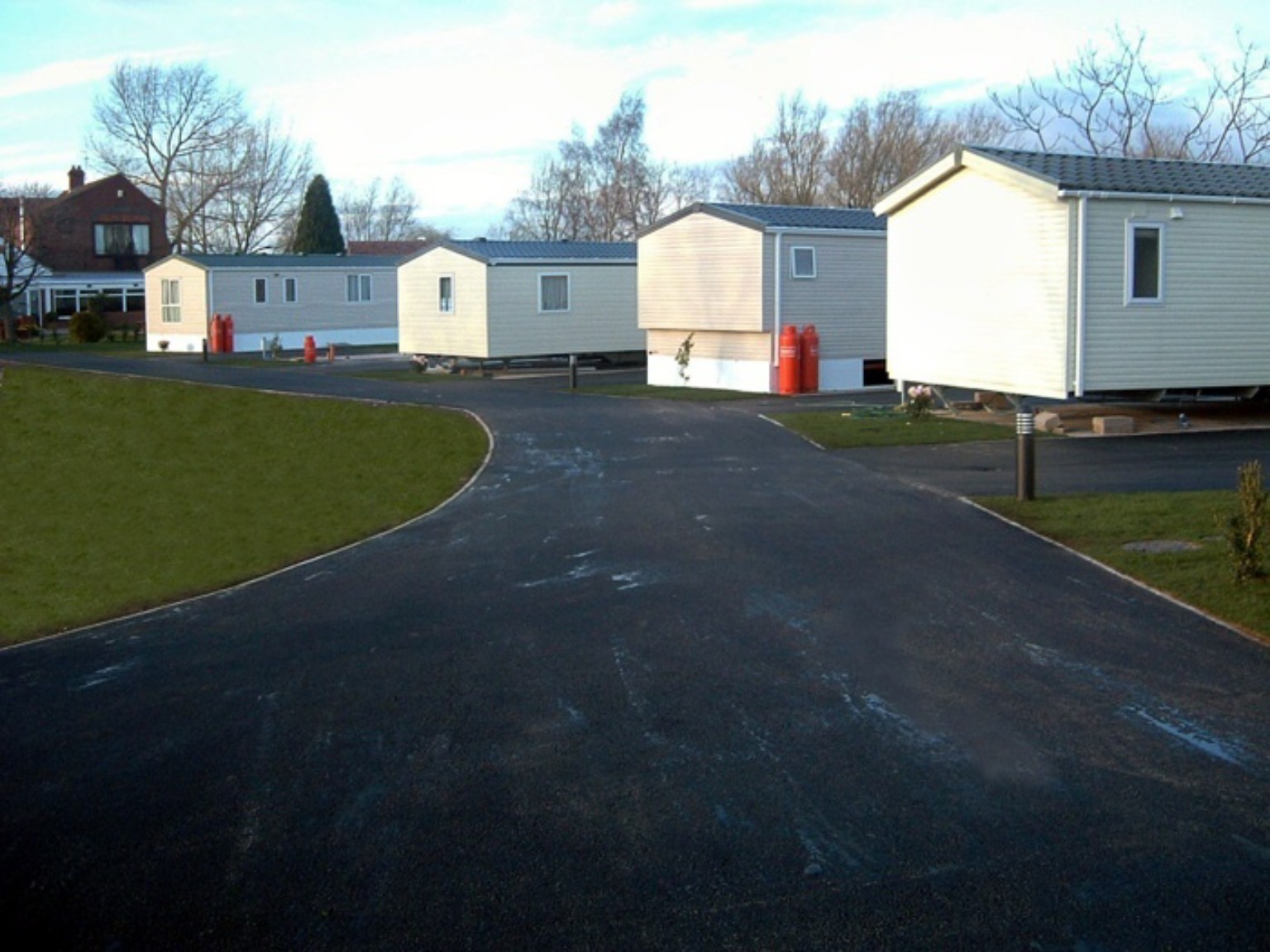 Finished machine-laid tarmac roadway curving between caravans at a caravan park in Berwick-upon-Tweed