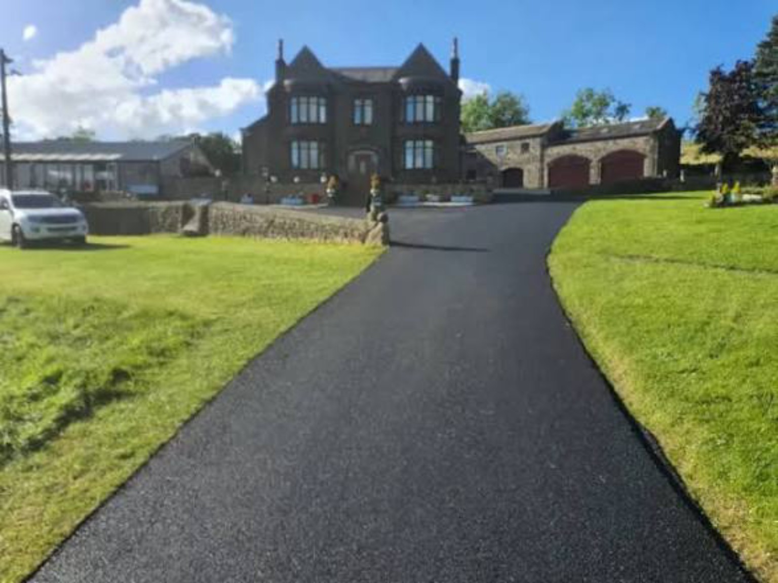 New tarmac approach between lawns leading to a house and farm buildings near Brechin in Angus, Scotland