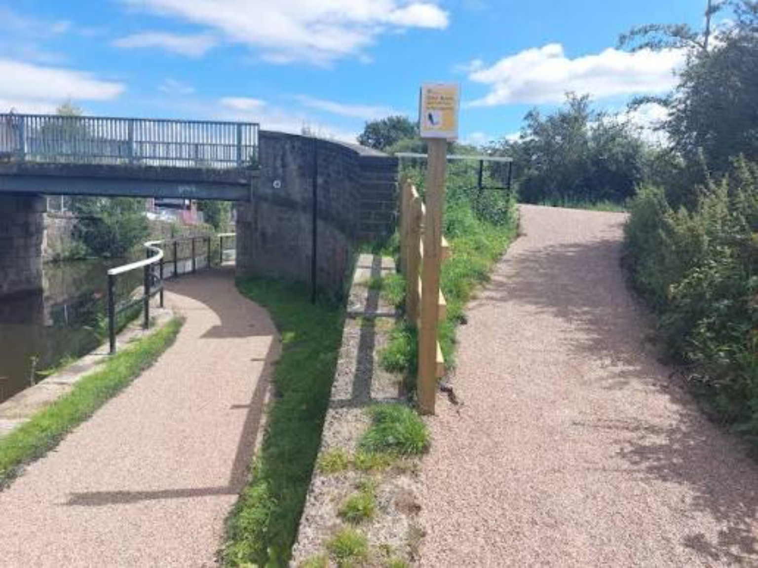 Finished canal-side footpath and towpath with a light stone surface beside a bridge