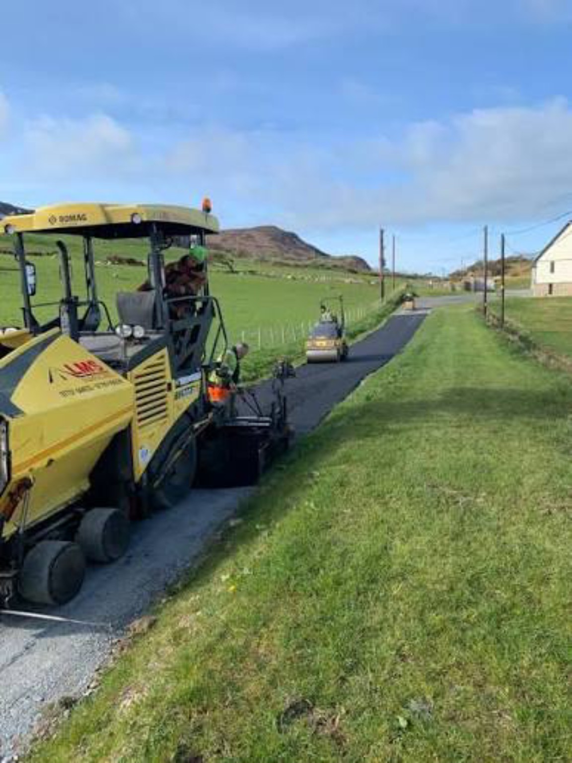 Paver and roller working on a farm lane in Dumbarton during hot tarmac resurfacing
