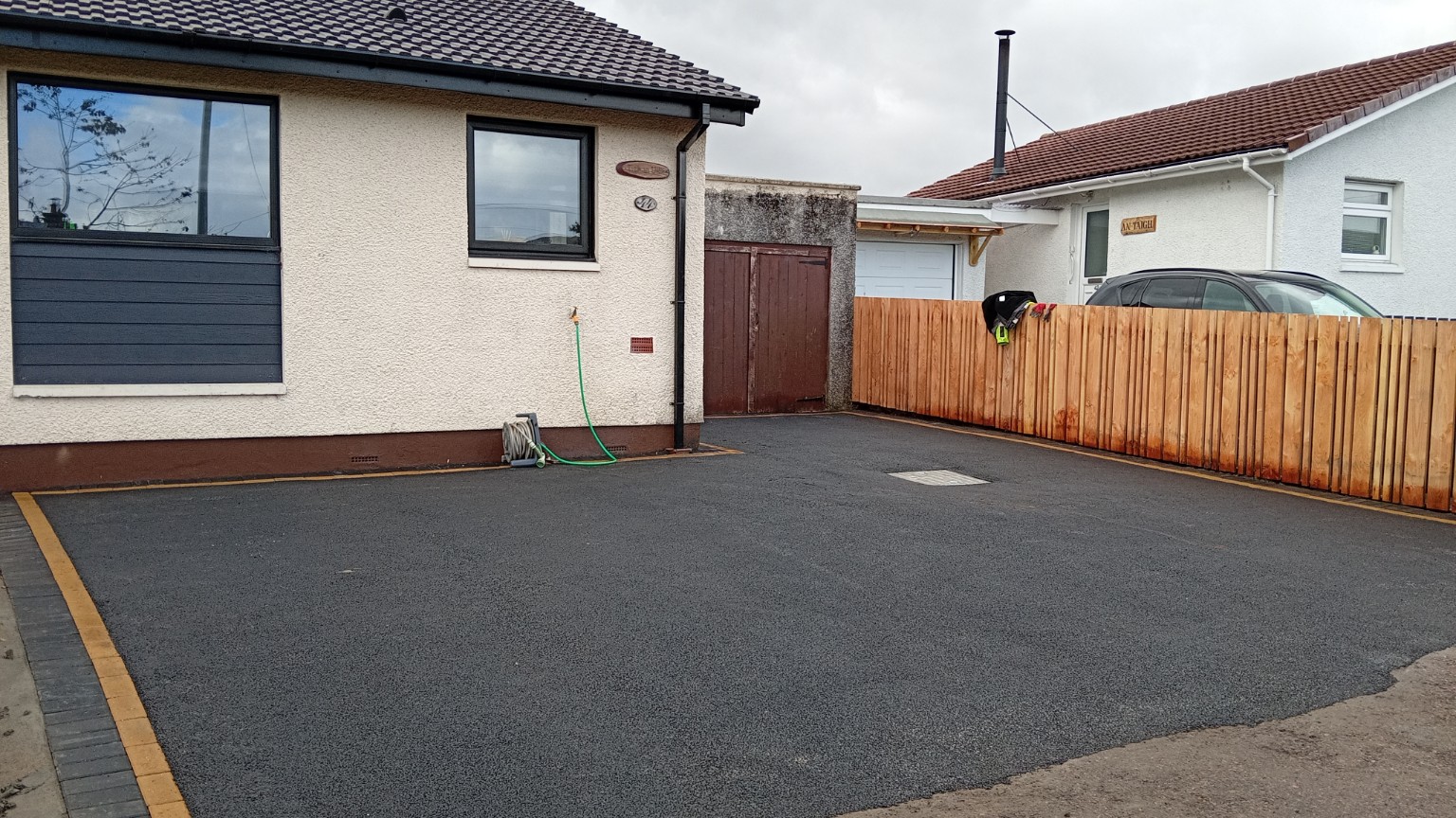 Completed tarmac driveway in Fort William with a charcoal and buff block-paved border across the front of the bungalow