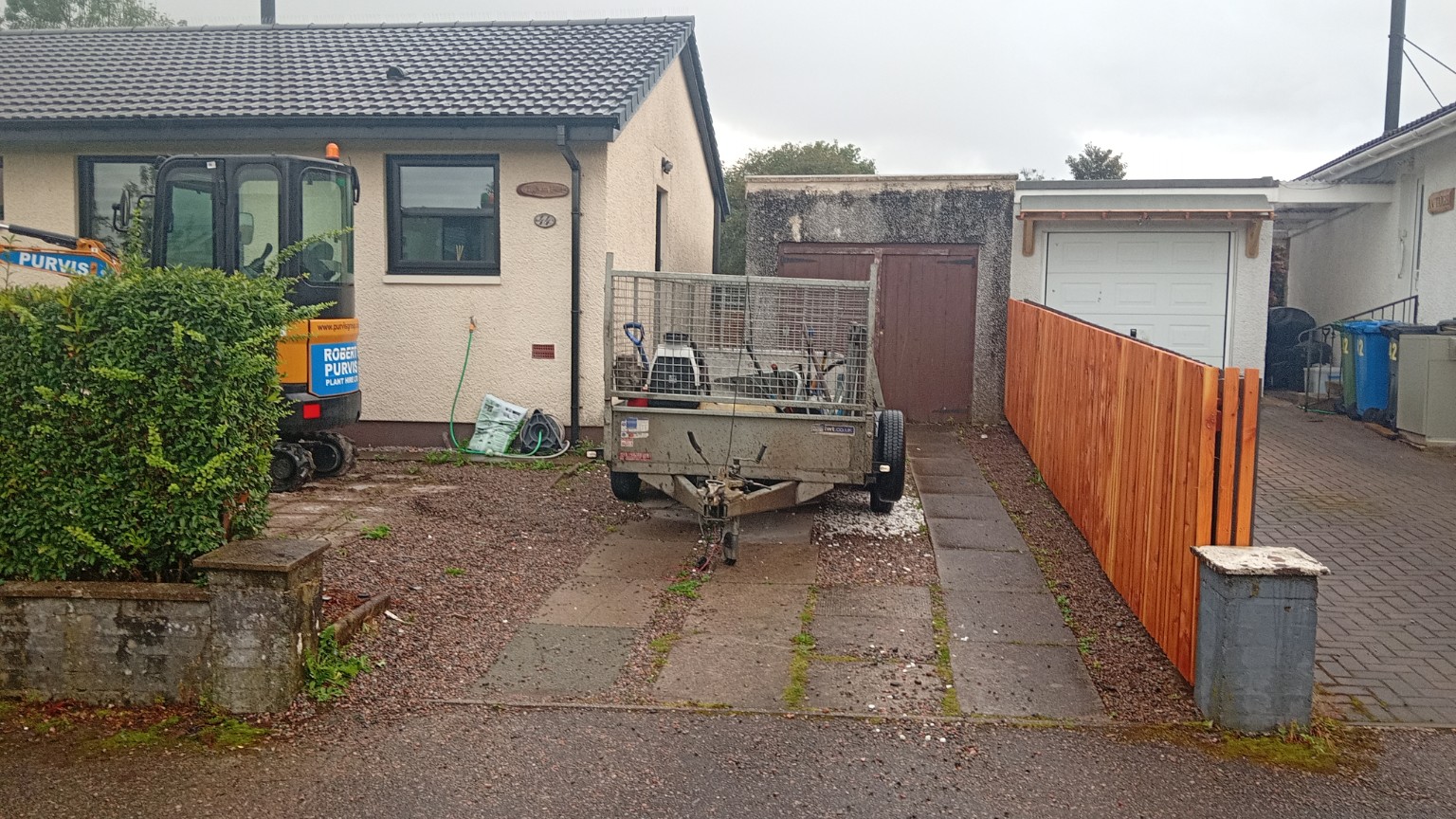 Fort William driveway before work, showing concrete paving strips and gravel leading to the garage