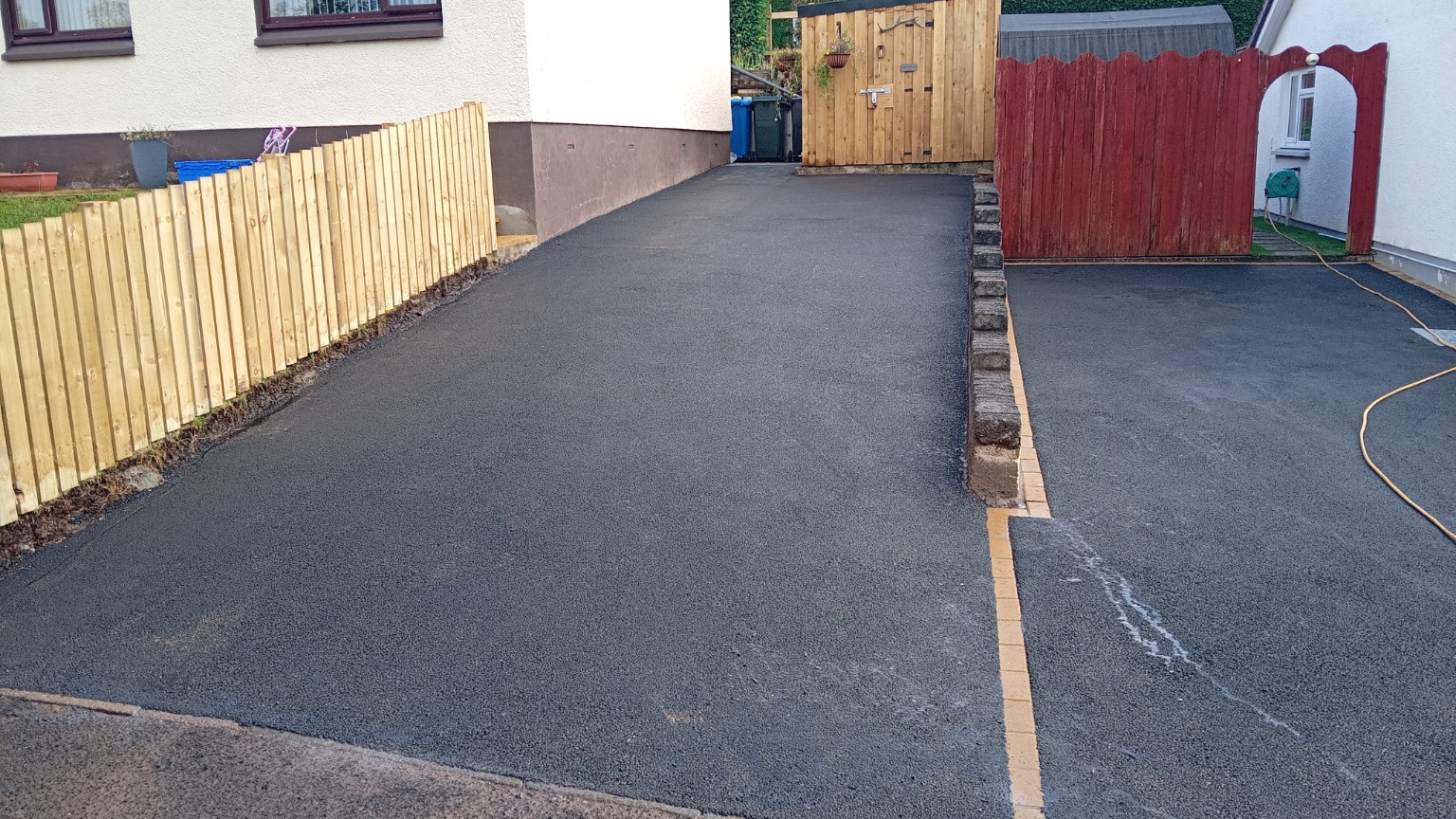 Two completed tarmac driveways in Fort William, one with a straightforward tarmac finish and the other with a picture-frame block-paved border