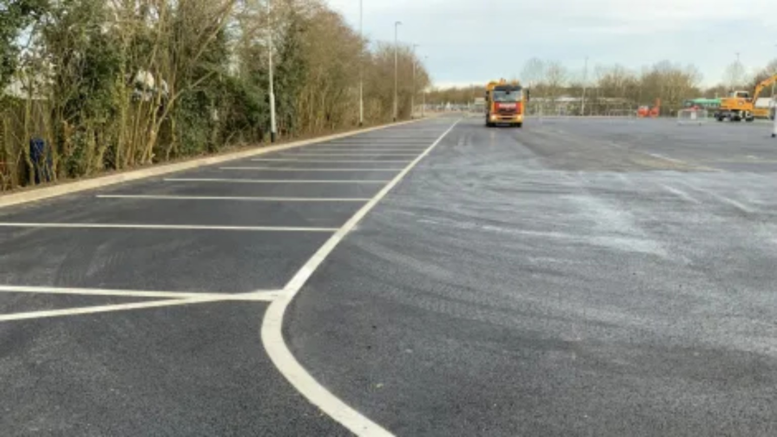 Resurfaced tarmac car park in Inverness with a row of white-lined parking bays and a curved boundary line