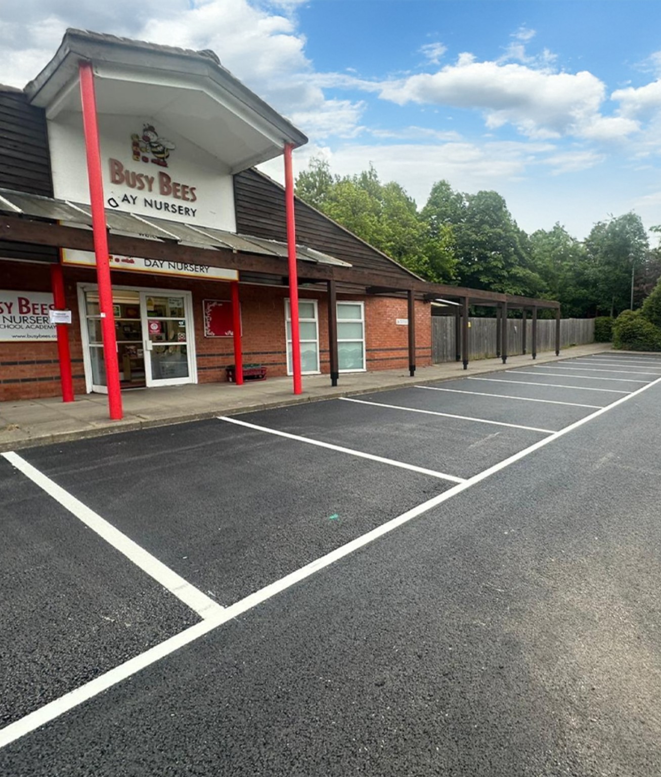 Resurfaced tarmac parking area outside a day nursery with fresh white parking bay markings