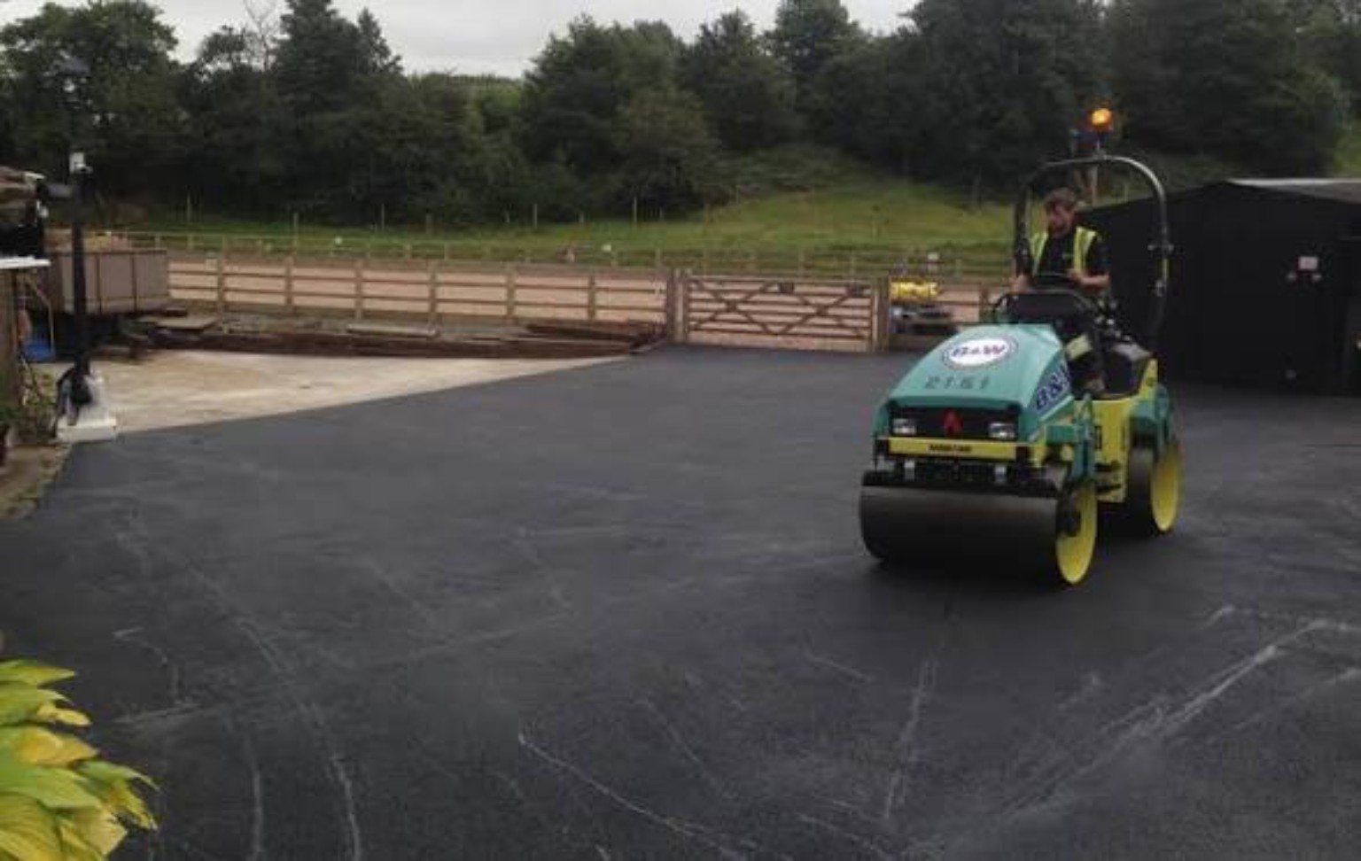 Roller compacting new asphalt in an equestrian centre courtyard beside entrance gates near Perth, Scotland