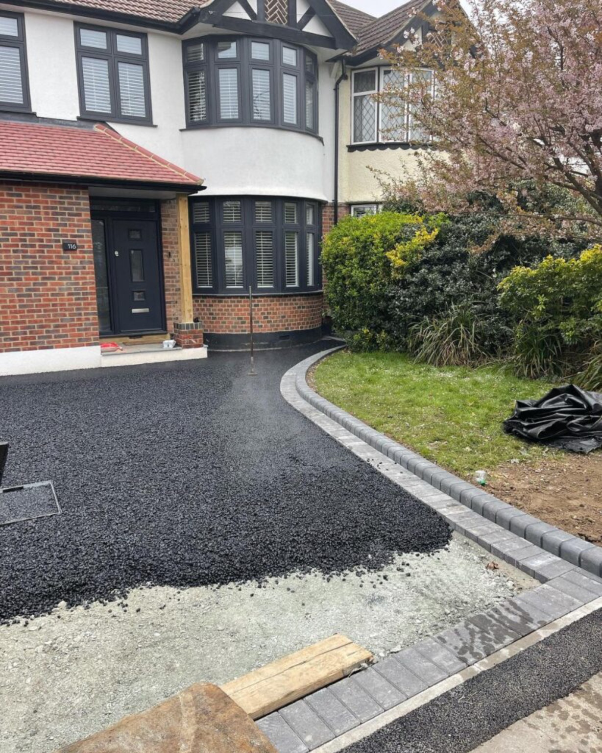 Tarmac driveway being surfaced in Prestwick, Ayrshire, with curved grey Marshalls block-paved borders and exposed prepared base at the front