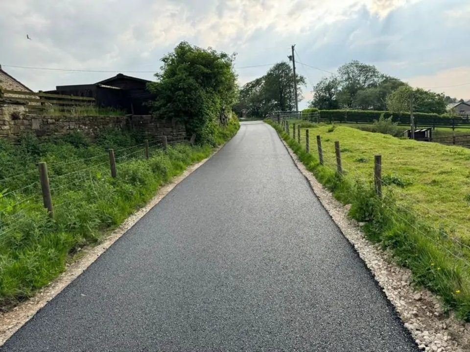 Completed machine-laid tarmac farm lane near Perth beside the farm buildings and field fence