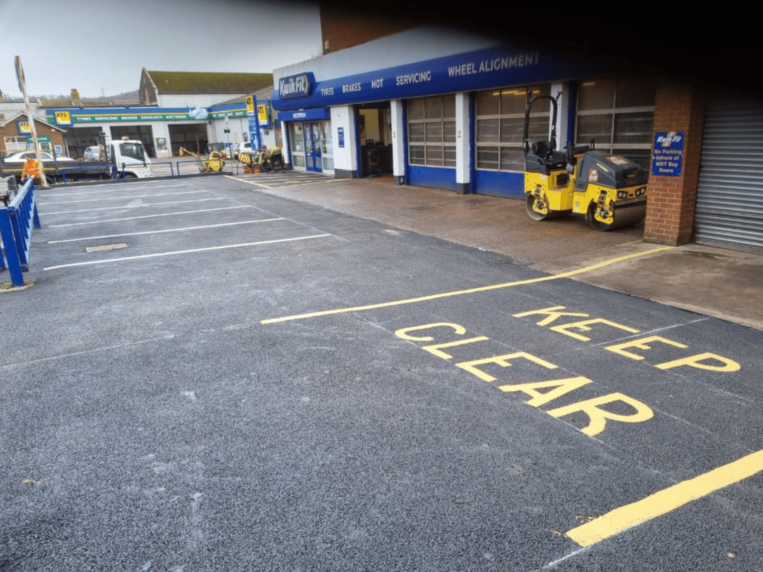 Kwik Fit tyre centre forecourt in the Scottish Borders following tarmac repairs, with parking bays and a keep-clear area