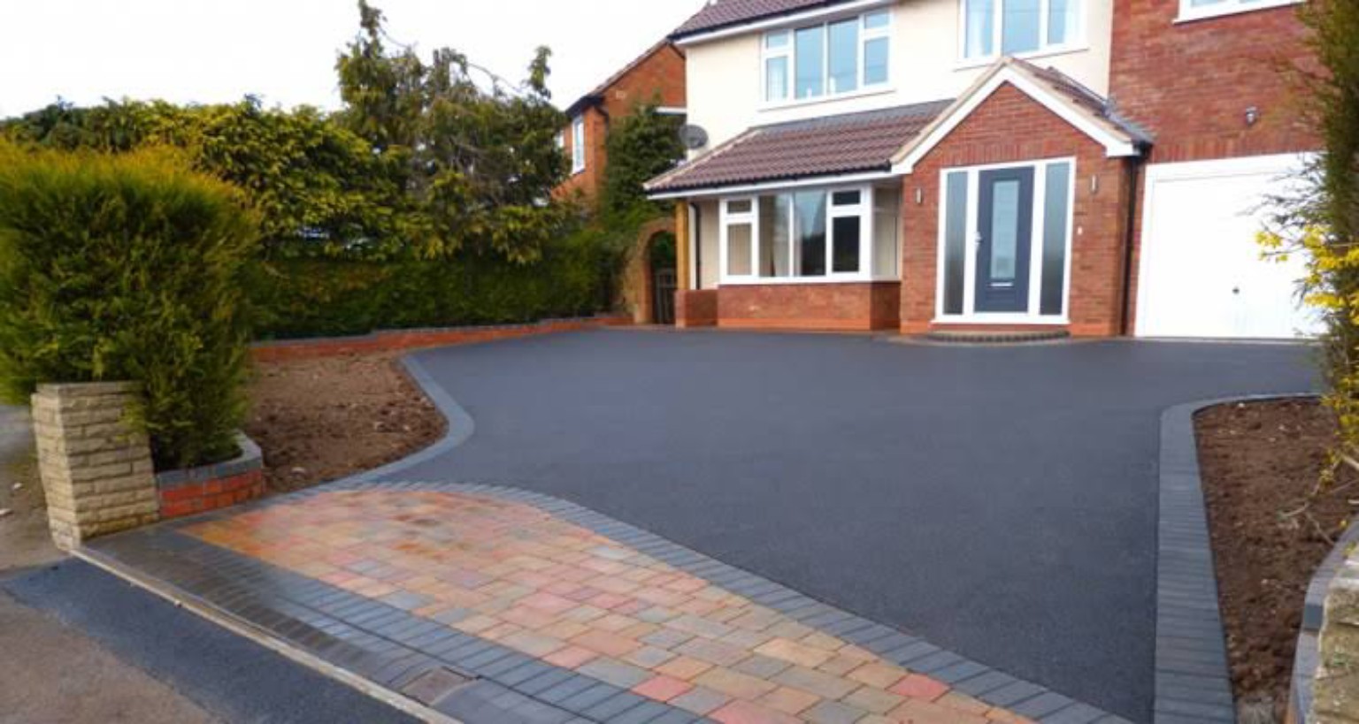 Finished tarmac driveway with curved charcoal block borders and a multicoloured block-paved entrance
